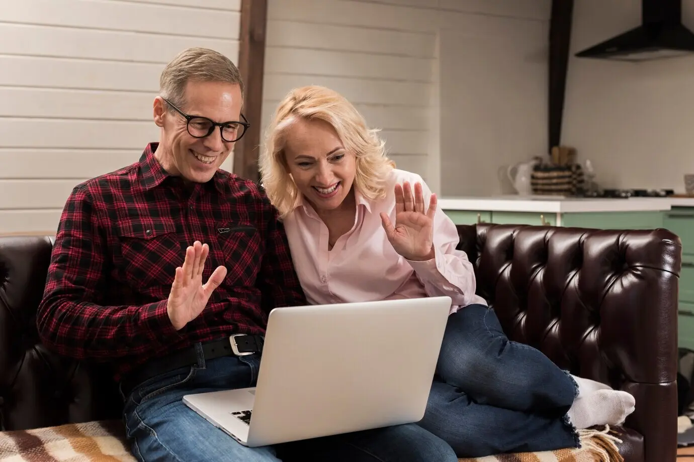 Счастливые родители на диване машут ноутбуку.