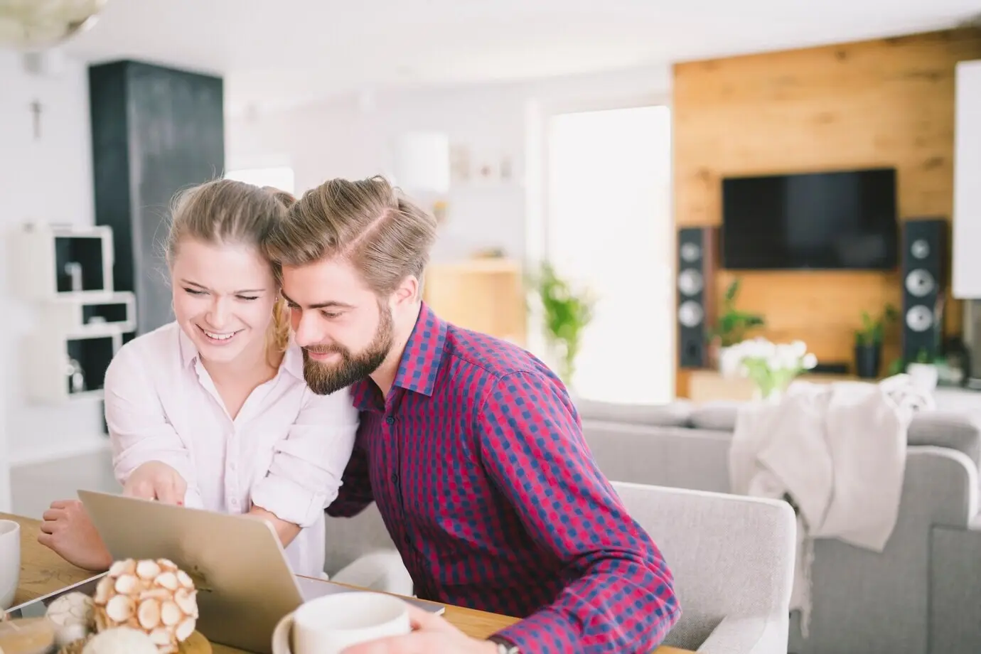 Весёлая молодая пара пользуется ноутбуком.